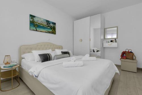 马卡尔斯卡Hortenzija Apartments的白色客房的两张床,拥有白色的墙壁