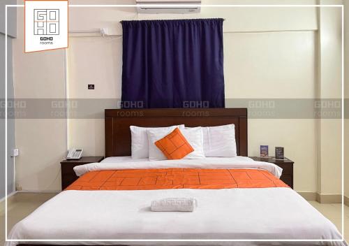 卡拉奇GOHO Rooms 10th Commercial的一间卧室配有一张带橙色和白色枕头的大床