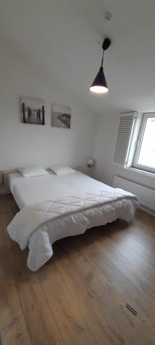 克诺克－海斯特de blinker的卧室铺有木地板,配有一张白色的床。