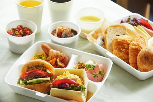 东京ICI HOTEL Ueno Shin Okachimachi的一张桌子上放着三盘三明治和点心