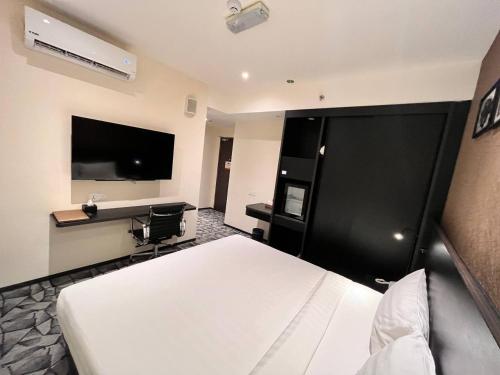 吉隆坡Hotel Aman Kuala Lumpur的配有一张床和一台平面电视的酒店客房