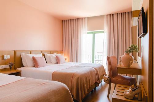 法蒂玛Hotel Santo António de Fátima的酒店客房设有两张床和窗户。