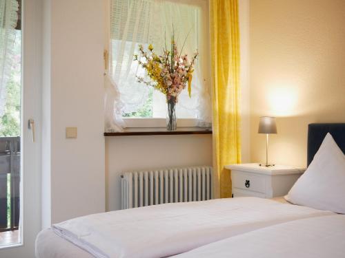 塞埃巴克Seebach-Hotel的卧室配有一张床,窗户上放着花瓶
