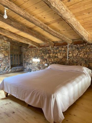 瑞达里那EL PALLER的卧室配有石墙内的白色床