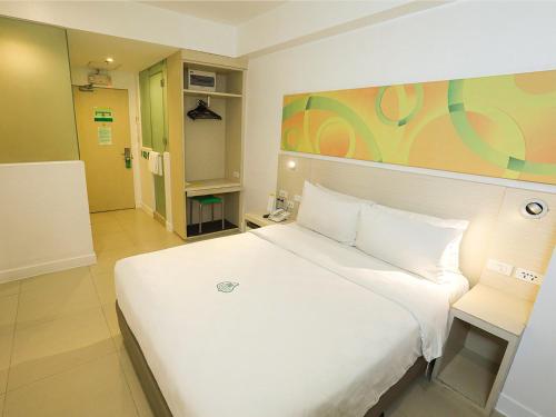 马尼拉Go Hotels Manila Airport Road的一间带白色床的卧室和一间带门的房间