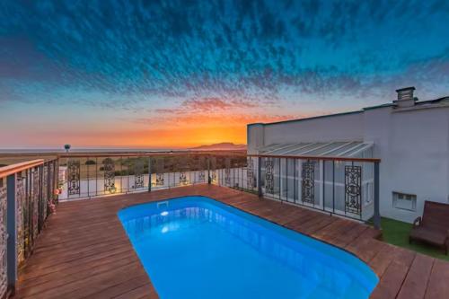 塔里法BOMBAYARTE APARTHOTEL TARIFA的一座享有日落美景的别墅甲板上的游泳池