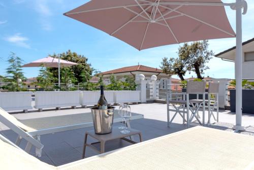 利多迪卡马约雷Lido Luxury Villas的坐在带桌子和遮阳伞的庭院里的一瓶葡萄酒