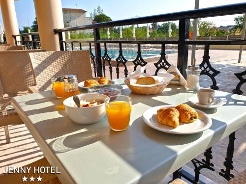 拉加纳斯Jenny Hotel的阳台上的桌子上摆放着早餐食品和橙汁