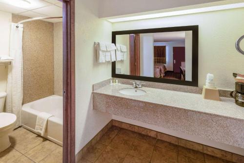 塞金Super 8 by Wyndham Seguin的一间带水槽、卫生间和镜子的浴室