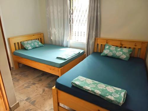 达累斯萨拉姆Tulivu House -2bedroom vacation home close to the beach的带窗户的客房内设有两张单人床。