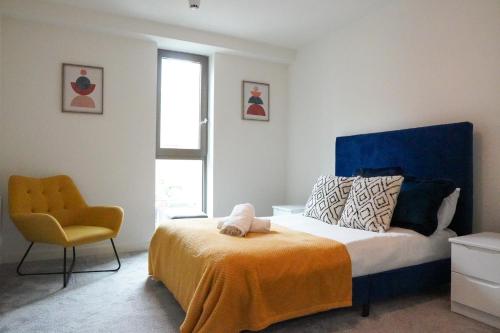 曼彻斯特Luxury Townhouse In Central Manchester的一间卧室配有一张带蓝色床头板和黄色椅子的床
