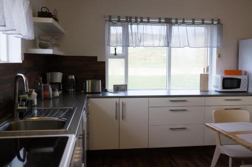 ÞingeyjarsveitGuesthouse Helluland的厨房配有白色橱柜、水槽和窗户。