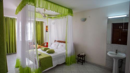 蒙巴萨Hotel Windsor-Mombasa的一间卧室配有一张带绿色窗帘和水槽的床