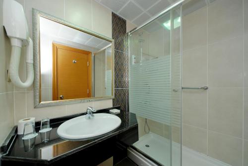马尔马里斯帕萨贝酒店的一间带水槽、镜子和淋浴的浴室