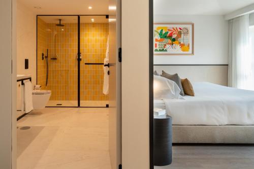 波尔图The Editory Garden Porto Hotel的一间卧室配有一张床,浴室设有淋浴。