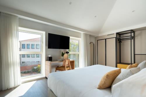 波尔图The Editory Garden Porto Hotel的一间卧室设有一张大床和一个大窗户