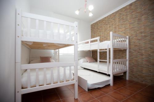 桑卢卡尔-德巴拉梅达Villa las Raices的砖墙客房内的2张白色双层床