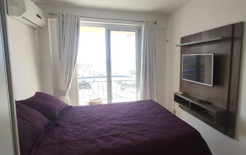 福塔莱萨Apto vista p/ mar 7º andar的一间卧室配有一张紫色的床和一台电视机
