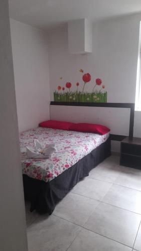 马尼萨莱斯El Amanecer La 27的墙上红色鲜花的房间里一张床位