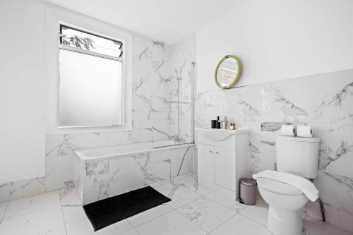 伦敦Parea Living - Hackney, 4-Bedroom Victorian House w Big Garden的白色的浴室设有卫生间和水槽。