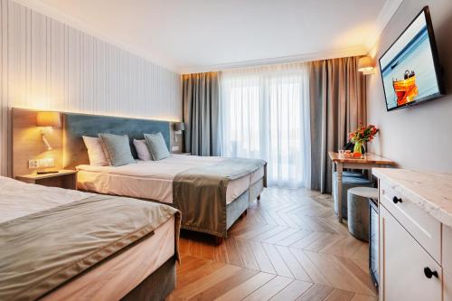 弗瓦迪斯瓦沃沃Belmar Park Resort & SPA的酒店客房设有两张床和电视。