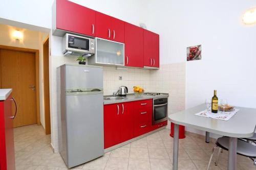 斯普利特Katarina apartman的厨房配有红色橱柜和白色冰箱