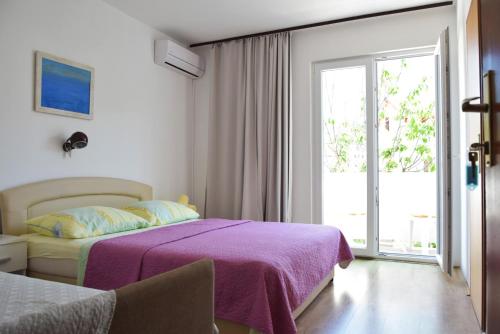 拉布Guest house Tina的一间卧室配有一张带紫色毯子的床和窗户。