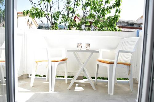 拉布Guest house Tina的阳台上配有白色的桌椅