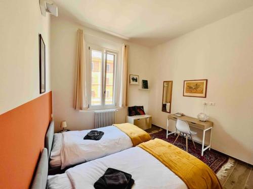 博洛尼亚Casa Bonita Bolognina的一间卧室设有两张床、一张桌子和一个窗口。