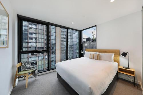 墨尔本The Canvas Apartment Hotel的卧室设有一张白色大床和大窗户