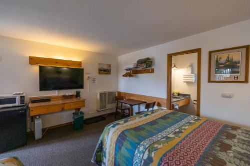 库克市Elk Horn Lodge的酒店客房配有一张床、一张书桌和一台电视。