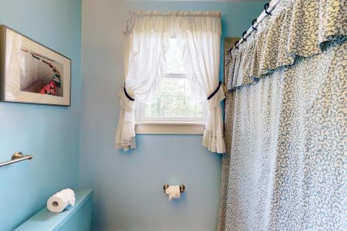 海恩尼斯Hyannis Beach House的蓝色的浴室设有窗户和窗帘