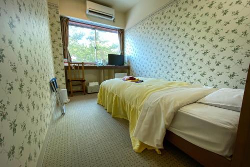 京丹后市大桥探戈温泉旅馆的一间卧室配有一张床、一张书桌和一个窗户。