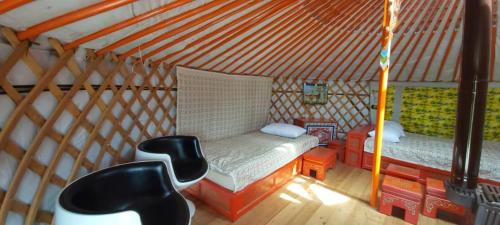 NarstKayak Camp, Tsonjinboldog的蒙古包内带一张床和两把椅子的房间