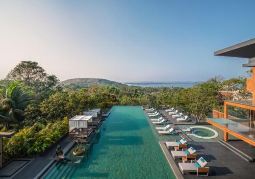 瓦加托JW Marriott Goa的度假村的无边泳池,配有躺椅