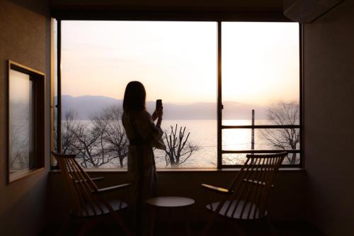 诹访市Suwakoen的从窗口拍下风景照片的女人
