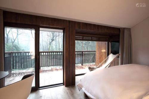 杭州杭州枫眠私享客栈的一间卧室设有一张床,阳台设有滑动玻璃门
