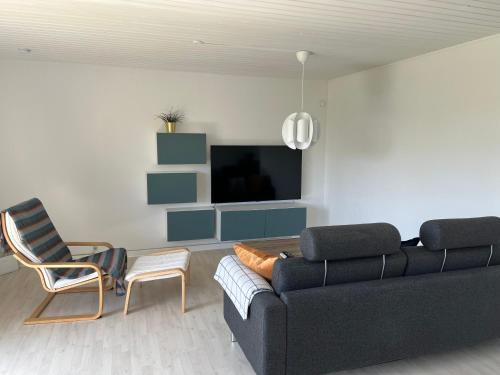 勒兹比The RED House, Rødbyhavn的客厅配有黑色沙发和椅子
