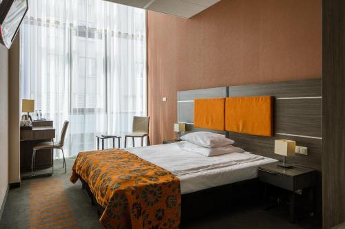 克拉科夫中心商务酒店的酒店客房设有一张床、一张书桌和窗户。