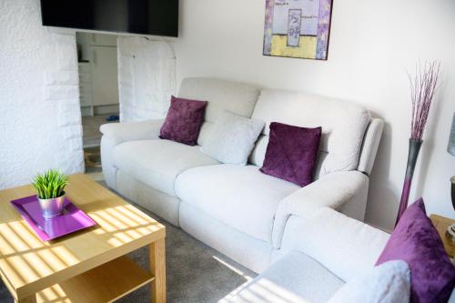 曼彻斯特Purple Blossom, cosy 2 bed apartment, near Didsbury, free parking的客厅配有白色沙发和紫色枕头