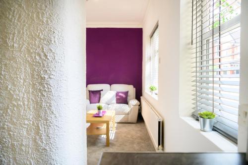 曼彻斯特Purple Blossom, cosy 2 bed apartment, near Didsbury, free parking的客厅设有紫色墙壁和沙发