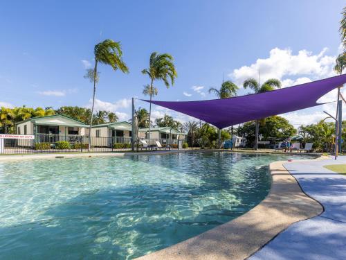鲍恩NRMA Bowen Beachfront Holiday Park的一座大型游泳池,上面有紫色的天篷