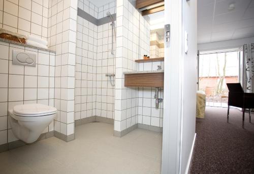 Hurup特宁格加德酒店的白色瓷砖浴室设有卫生间和窗户。