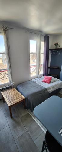 巴黎The heart of Montmartre的一间卧室配有一张床、一张桌子和两个窗户