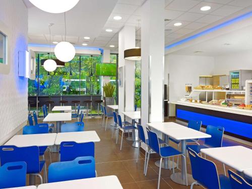 威斯巴登威斯巴登诺丹斯塔德宜必思快捷酒店 的一间设有白色桌子和蓝色椅子的自助餐厅