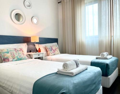 里斯本ABC Expo Apartment的一间卧室配有两张床,在一张搁脚凳上备有毛巾