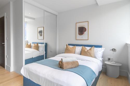 伦敦Livestay-Modern Apartments Next To Wembley Stadium的卧室配有蓝色和白色的床和镜子