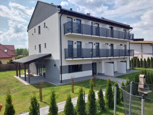 乌斯特卡VILLA EDEN USTKA wypoczynek dla dorosłych的白色的房子,设有蓝色的阳台和庭院