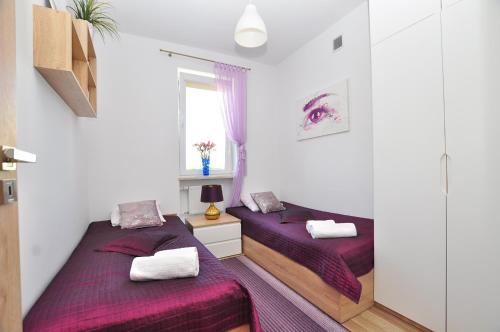 托伦Apartament Chełmiński的配有紫色床单的小客房内的两张床