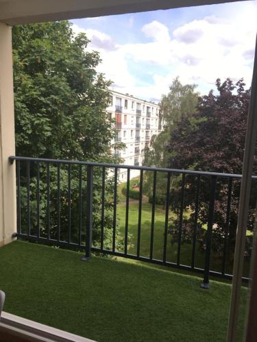 蒙圣埃尼昂Chambre dans appartement lumineux的阳台享有绿色草地和建筑的景致。